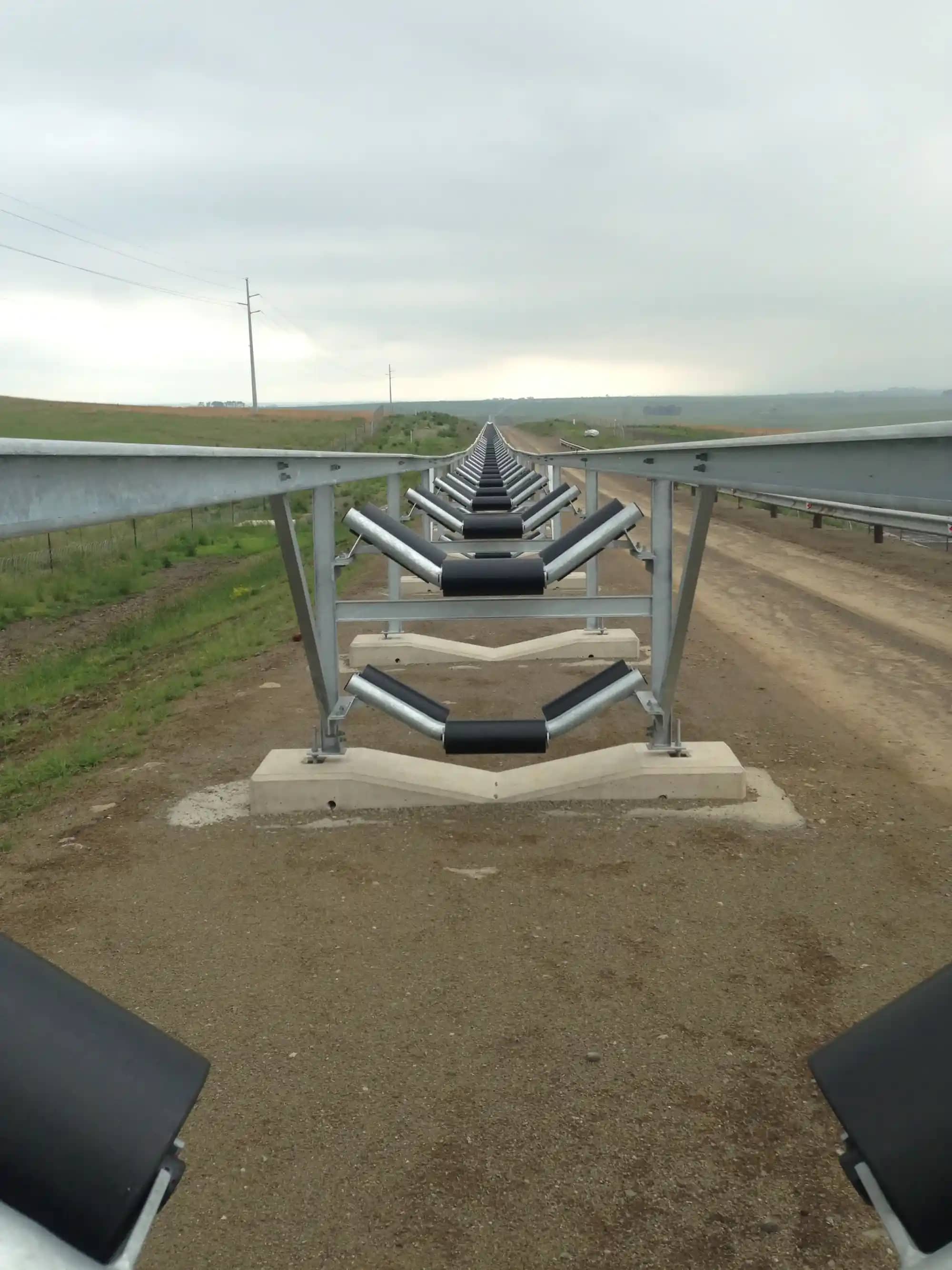 Impumelelo overland conveyor idlers with HDPE machined sleeves on steel roller bodies, installed for noise abatement